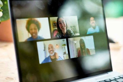 Laptop screen showing a five-person video call, all participants smiling